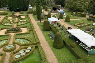 Chambre lumineuse avec un lit double, un canapé, un bureau en bois et une fenêtre donnant sur un espace vert.