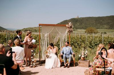 Village entouré de vignes et de collines verdoyantes sous un ciel partiellement nuageux.