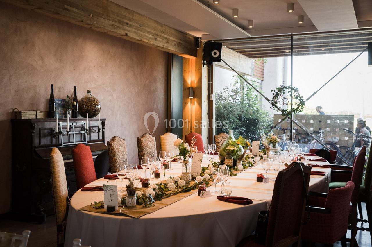 Grande table élégamment dressée dans une salle lumineuse avec des chaises variées et une décoration florale.