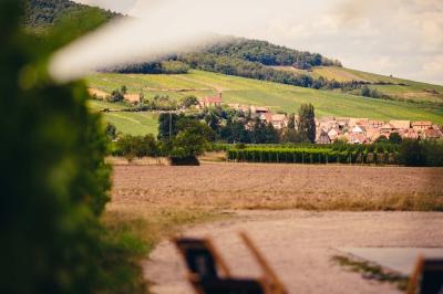 Village entouré de vignes et de collines verdoyantes sous un ciel partiellement nuageux.