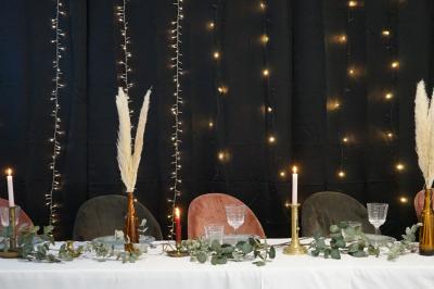 Arbre décoratif avec branches noires ornées de fleurs artificielles et de petites décorations suspendues.