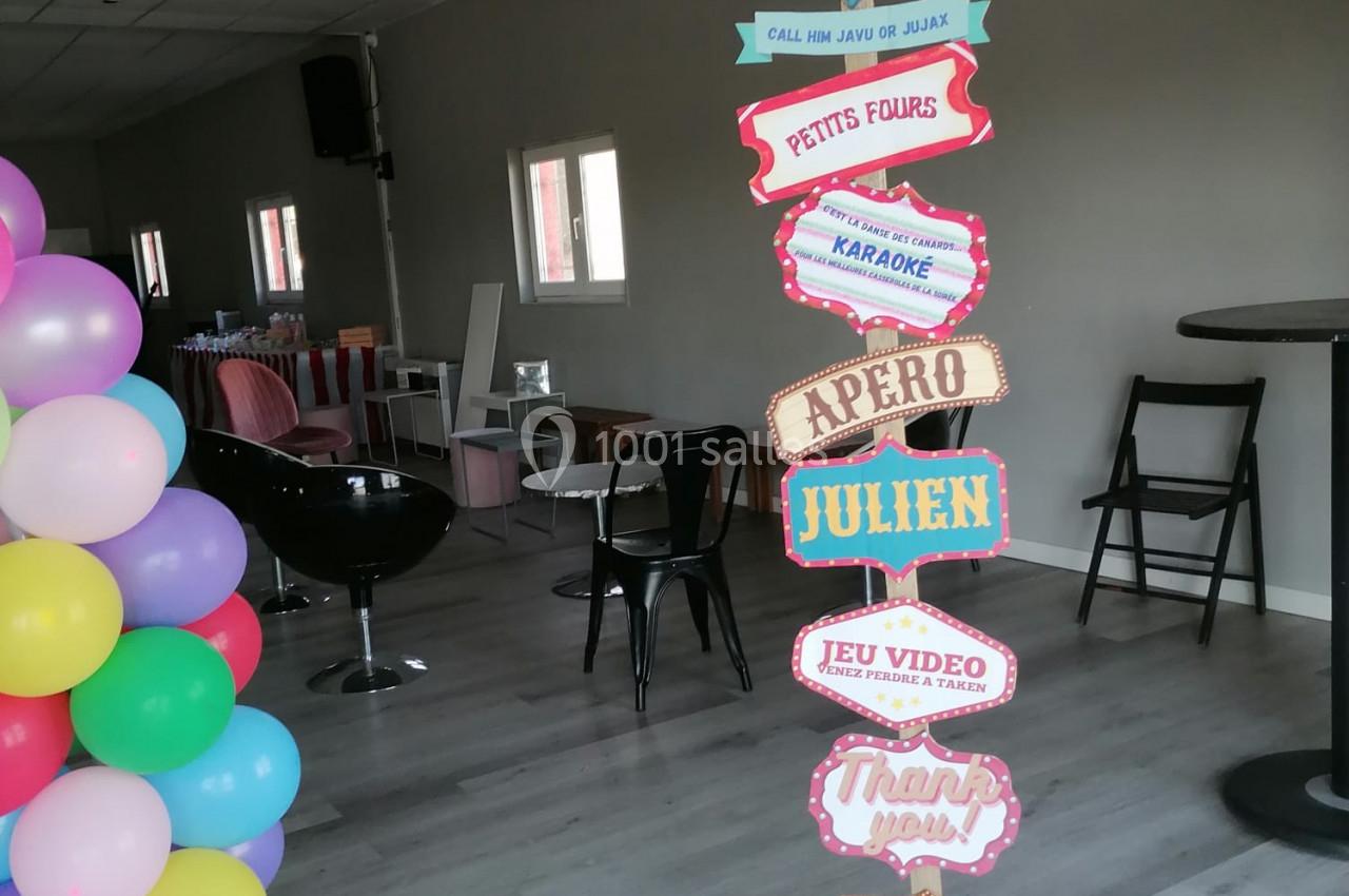Panneau coloré indiquant différentes activités et espaces festifs dans une salle décorée avec des ballons.