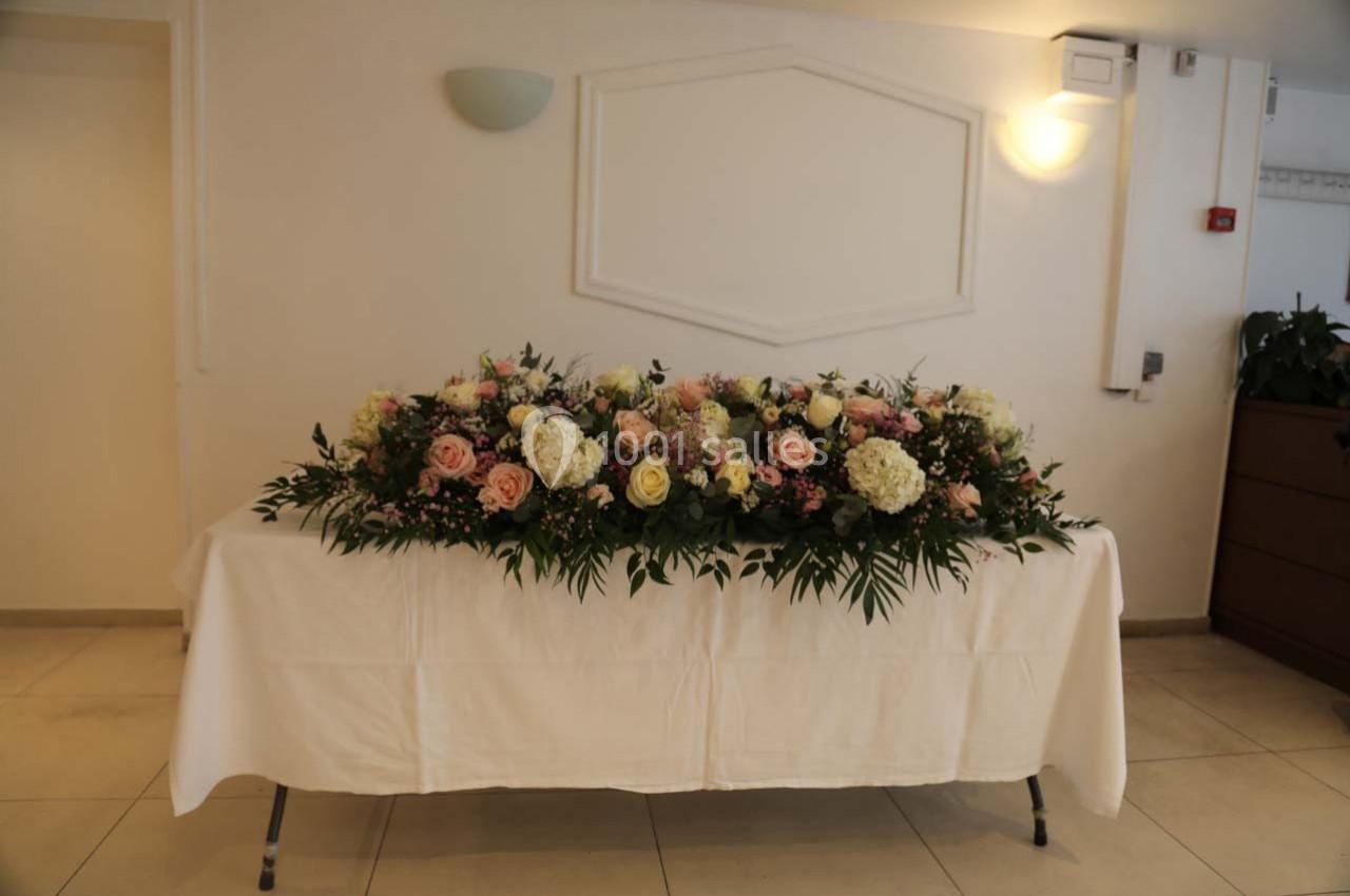 Arrangement floral coloré avec roses, hortensias et feuillage, posé sur une table recouverte d'une nappe blanche.