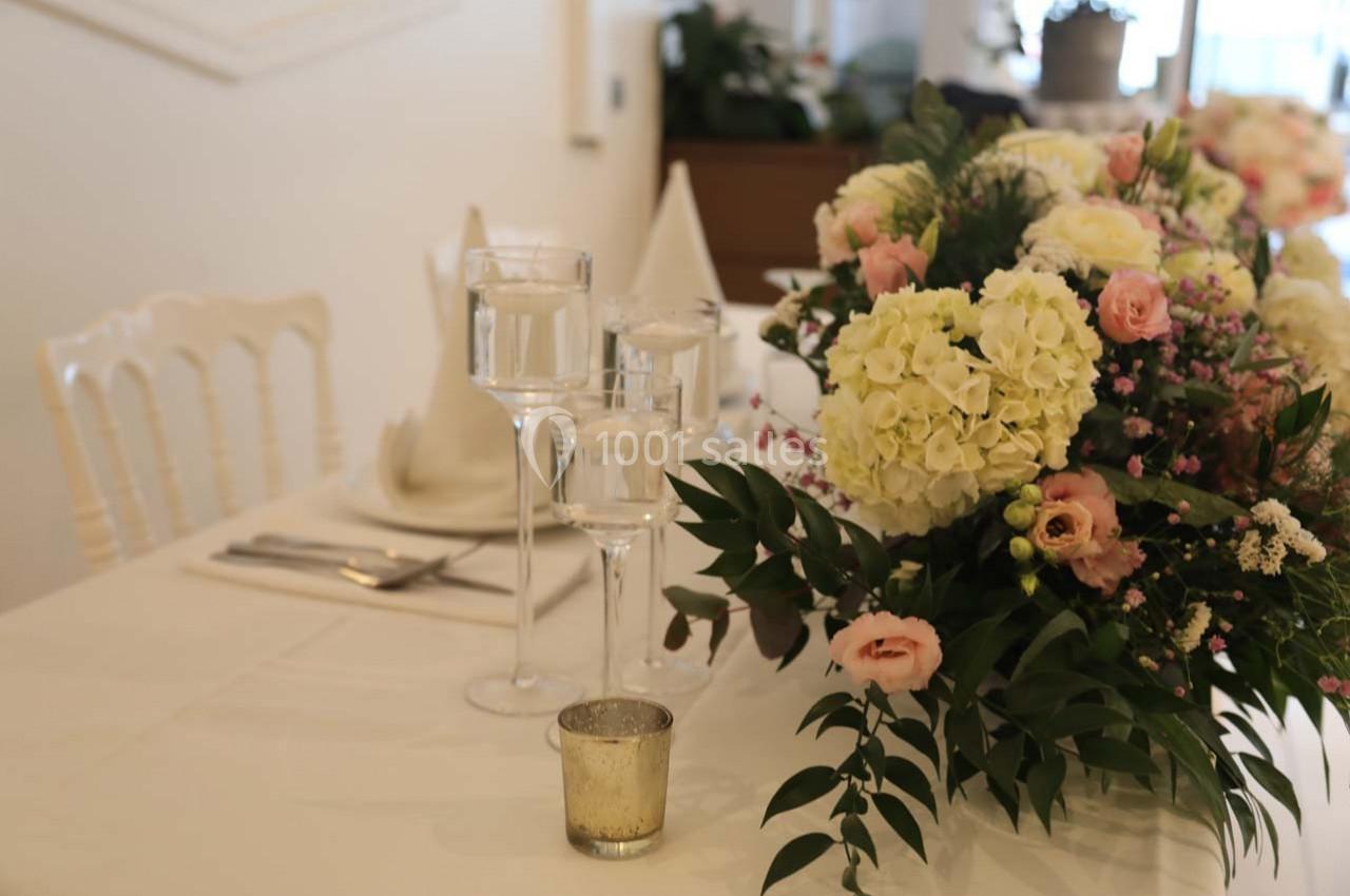 Table décorée avec un bouquet de fleurs pastel, des bougies et des serviettes pliées dans une ambiance élégante.