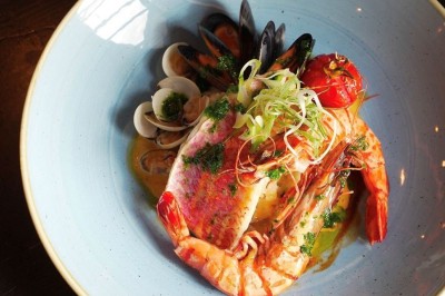 Assiette de pad thaï avec crevettes, tofu, coriandre, cacahuètes concassées et quartiers de citron vert.