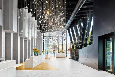 Espace de coworking lumineux avec canapé, étagères, plantes, et coin café équipé dans un décor moderne.