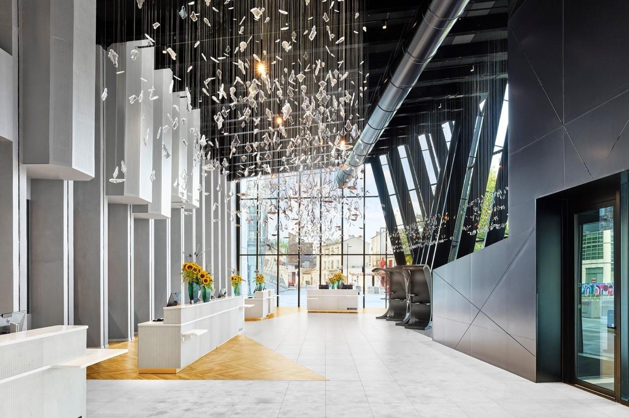 Hall moderne avec un plafond décoré de suspensions en verre, grandes baies vitrées et comptoirs d'accueil lumineux.