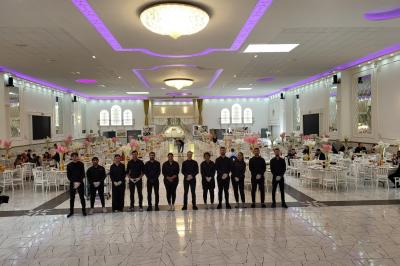 Allée centrale bordée de chaises blanches alignées, installée en extérieur sur une pelouse synthétique.