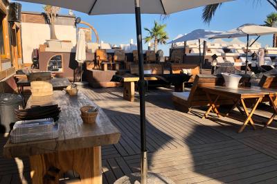 Verre de cocktail rouge avec glace pilée, mûres fraîches et une fleur violette, posé sur une table en bois.