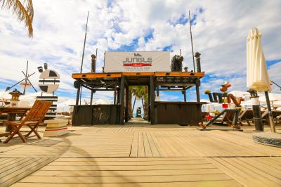 Verre de cocktail rouge avec glace pilée, mûres fraîches et une fleur violette, posé sur une table en bois.