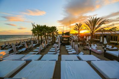 Verre de cocktail rouge avec glace pilée, mûres fraîches et une fleur violette, posé sur une table en bois.
