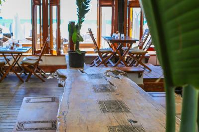 Verre de cocktail rouge avec glace pilée, mûres fraîches et une fleur violette, posé sur une table en bois.