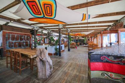 Verre de cocktail rouge avec glace pilée, mûres fraîches et une fleur violette, posé sur une table en bois.