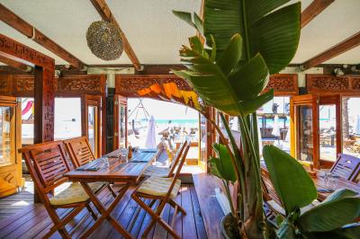 Verre de cocktail rouge avec glace pilée, mûres fraîches et une fleur violette, posé sur une table en bois.