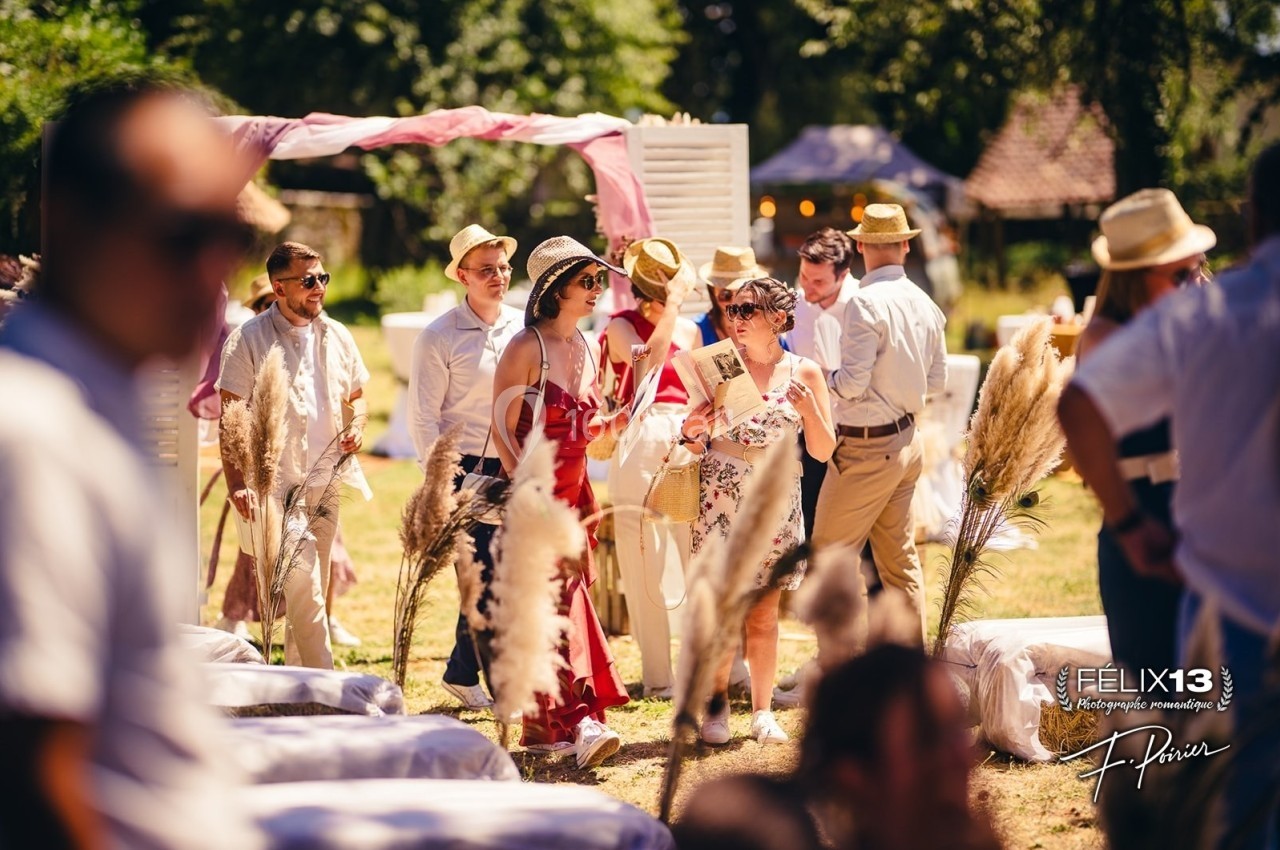 Groupe de personnes élégamment vêtues discutant lors d'un événement en plein air, entourées de décorations naturelles.