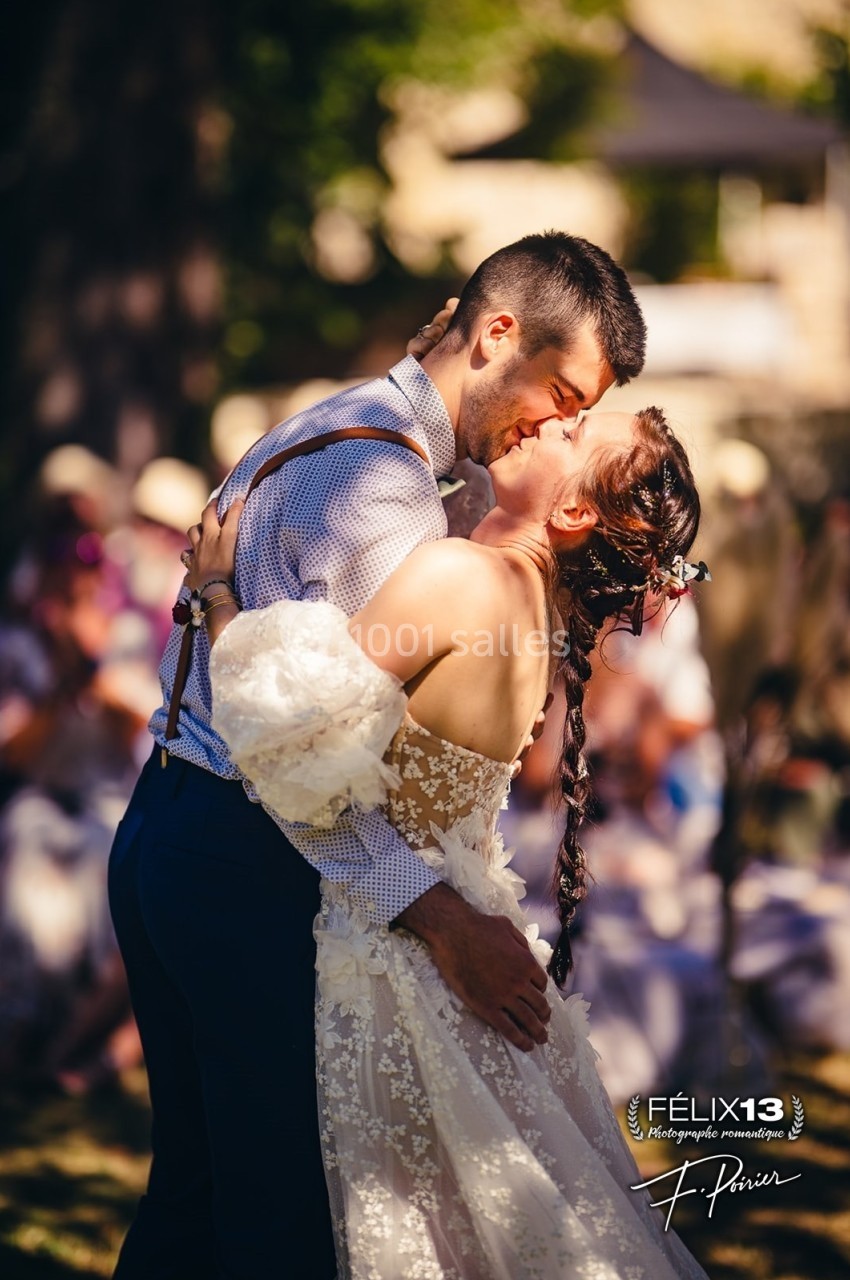 Un couple échange un moment tendre en dansant lors d'une cérémonie en extérieur, sous une lumière ensoleillée.