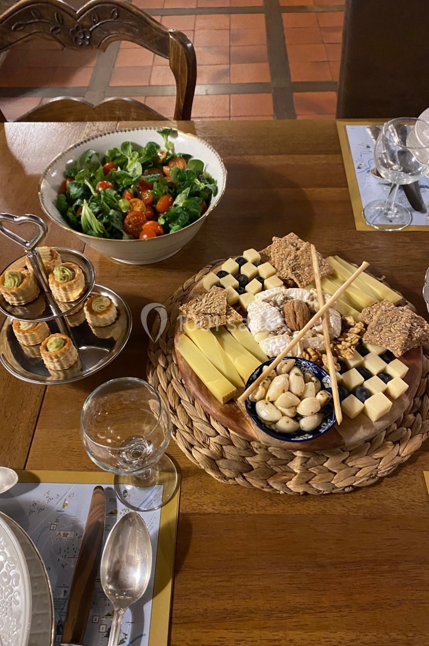 Plateau de fromages, noix et crackers accompagné d'une salade verte et d'amuse-bouches sur une table dressée.