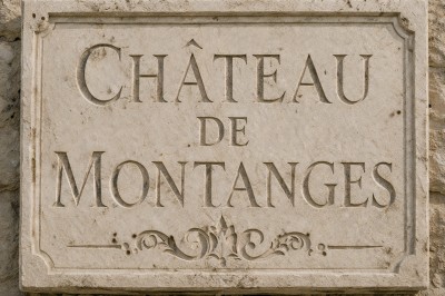 Plaque en pierre gravée avec des inscriptions dorées et un motif de croix ailée au-dessus du texte.