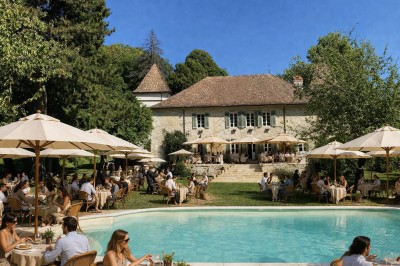 Plaque en pierre gravée avec des inscriptions dorées et un motif de croix ailée au-dessus du texte.