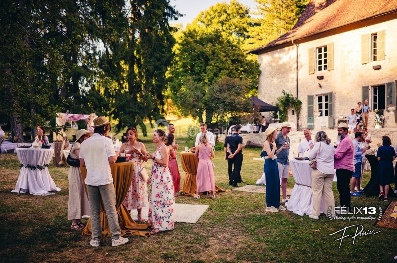 Groupe de personnes discutant et partageant un moment convivial dans le jardin d'une maison en pierre par une journée…