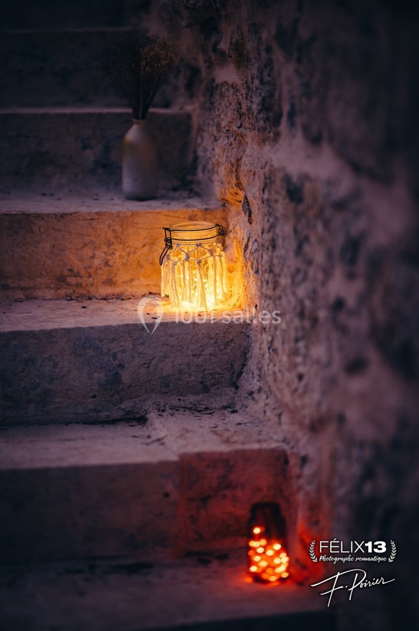 Bocal lumineux et petite lanterne rouge éclairant des marches en pierre dans une ambiance tamisée.