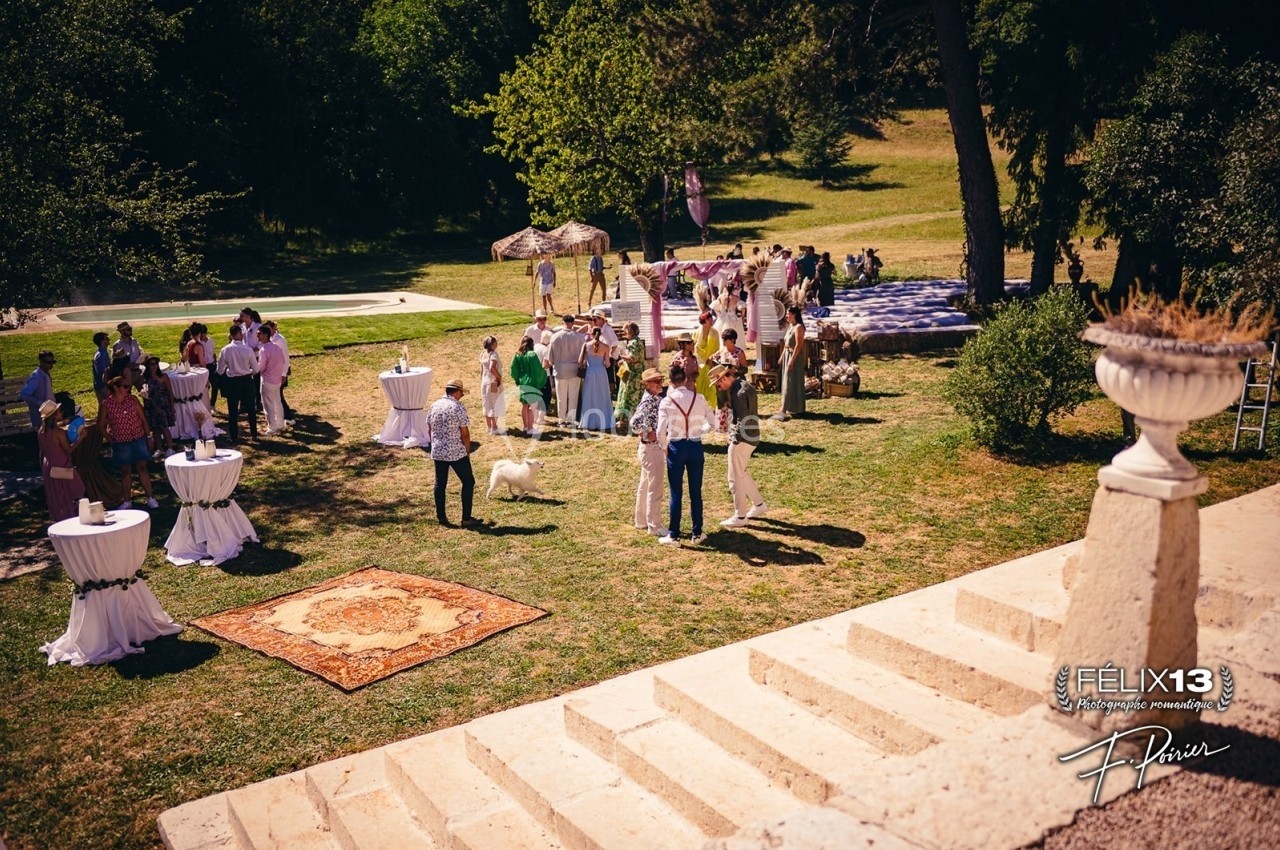Groupe de personnes rassemblées dans un jardin pour un événement, avec tables hautes, tapis et piscine en arrière-plan.