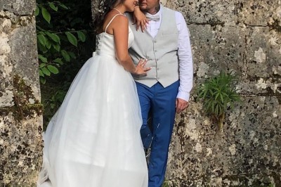 Plaque en pierre gravée avec des inscriptions dorées et un motif de croix ailée au-dessus du texte.