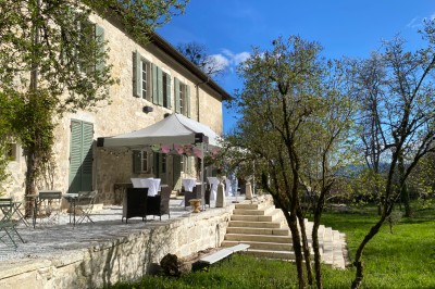 Plaque en pierre gravée avec des inscriptions dorées et un motif de croix ailée au-dessus du texte.