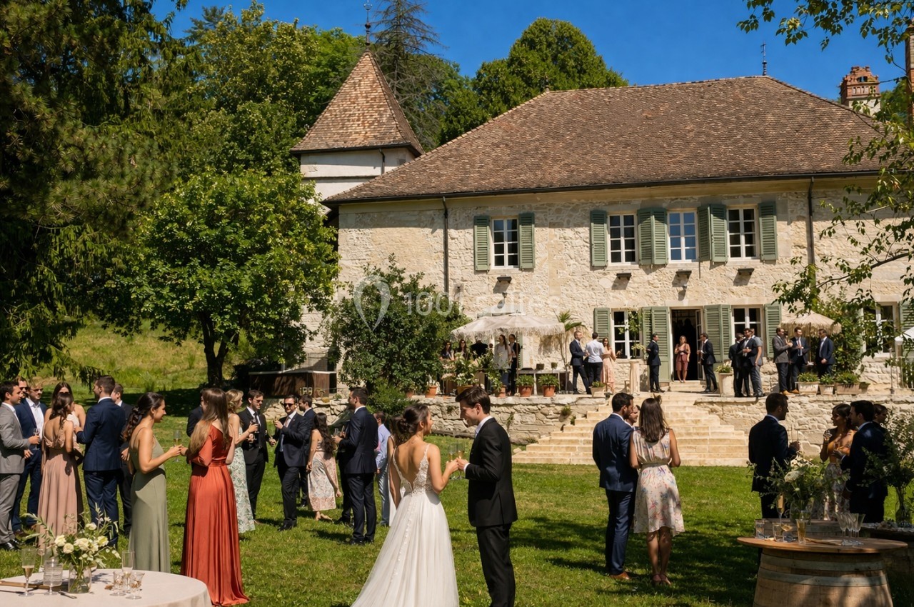 Groupe de personnes rassemblées dans le jardin d'une grande maison en pierre lors d'un événement en plein air.