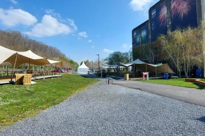 Salle lumineuse avec de grandes baies vitrées, tables dressées avec nappes grises, vaisselle et décoration florale.