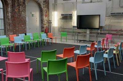 Salle lumineuse avec de grandes baies vitrées, tables dressées avec nappes grises, vaisselle et décoration florale.