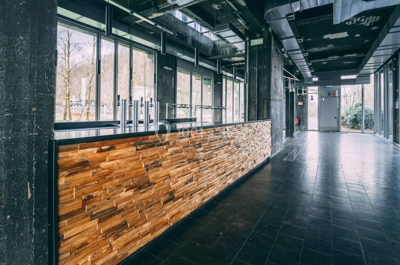 Comptoir en bois dans un espace moderne avec de grandes baies vitrées laissant entrer la lumière naturelle.