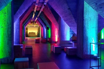 Salle lumineuse avec de grandes baies vitrées, tables dressées avec nappes grises, vaisselle et décoration florale.