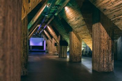 Salle lumineuse avec de grandes baies vitrées, tables dressées avec nappes grises, vaisselle et décoration florale.