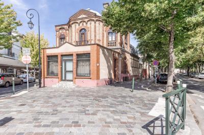 Cuisine moderne avec îlot central noir, chaises hautes, meubles rouges, électroménagers intégrés et carrelage blanc.
