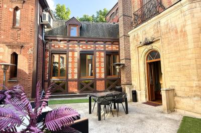 Cuisine moderne avec îlot central noir, chaises hautes, meubles rouges, électroménagers intégrés et carrelage blanc.