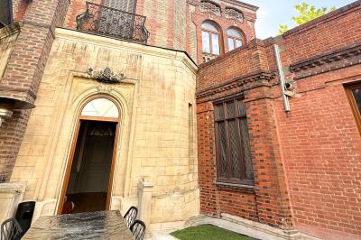 Cuisine moderne avec îlot central noir, chaises hautes, meubles rouges, électroménagers intégrés et carrelage blanc.