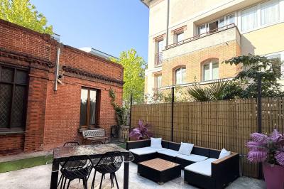 Cuisine moderne avec îlot central noir, chaises hautes, meubles rouges, électroménagers intégrés et carrelage blanc.