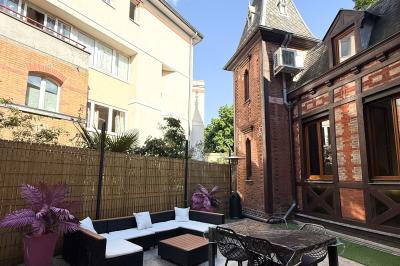 Cuisine moderne avec îlot central noir, chaises hautes, meubles rouges, électroménagers intégrés et carrelage blanc.