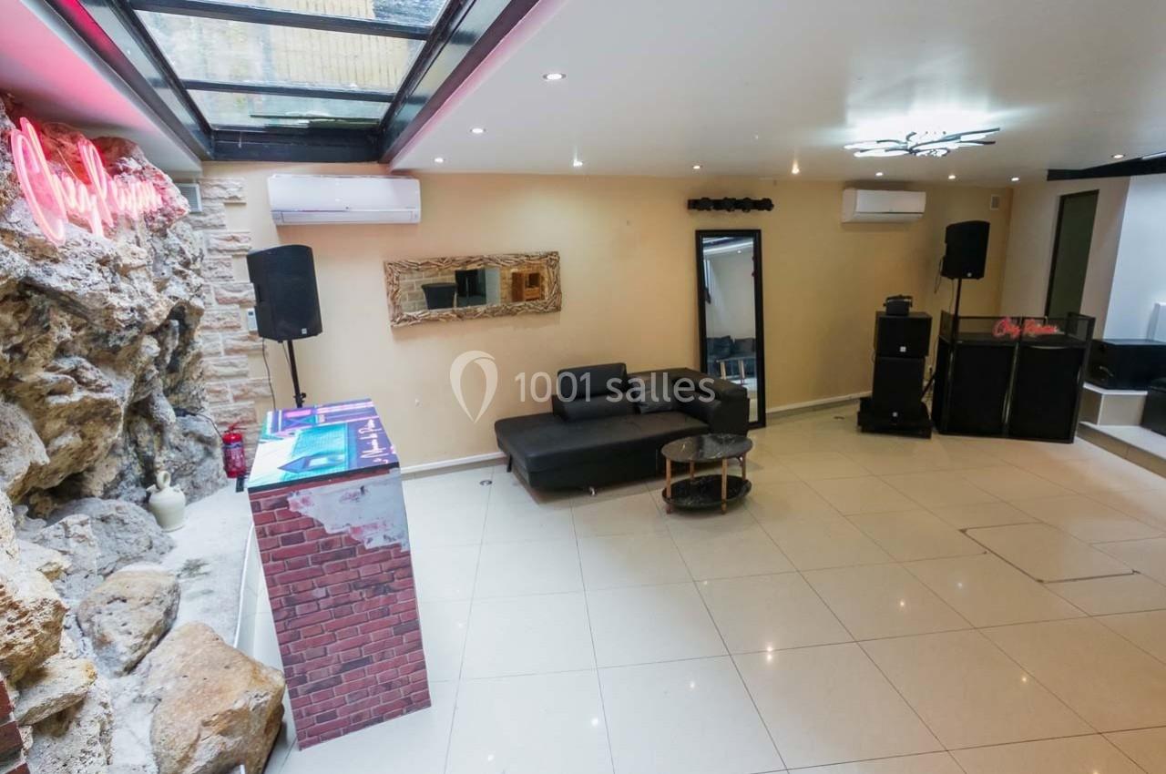 Salle moderne avec canapé, table basse, bar en briques, mur en pierre, éclairage au plafond et verrière.