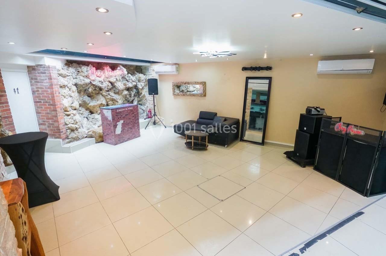 Salle lumineuse avec sol en carrelage, canapé, miroir, comptoir en briques et équipements audio.