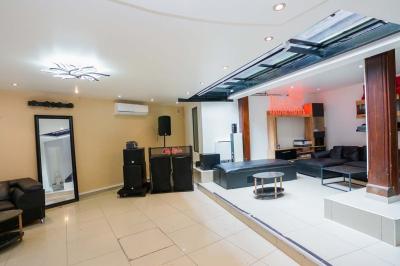 Cuisine moderne avec îlot central noir, chaises hautes, meubles rouges, électroménagers intégrés et carrelage blanc.