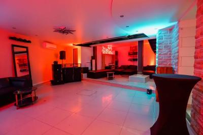 Cuisine moderne avec îlot central noir, chaises hautes, meubles rouges, électroménagers intégrés et carrelage blanc.