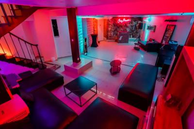 Cuisine moderne avec îlot central noir, chaises hautes, meubles rouges, électroménagers intégrés et carrelage blanc.