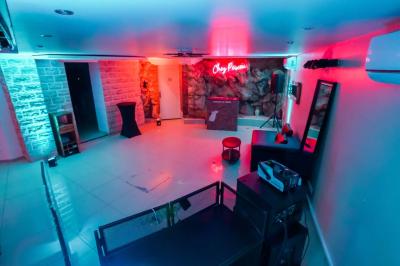 Cuisine moderne avec îlot central noir, chaises hautes, meubles rouges, électroménagers intégrés et carrelage blanc.