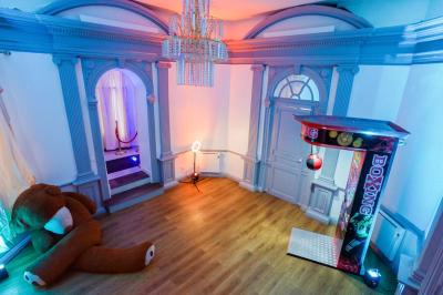 Cuisine moderne avec îlot central noir, chaises hautes, meubles rouges, électroménagers intégrés et carrelage blanc.