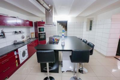 Cuisine moderne avec îlot central noir, chaises hautes, meubles rouges, électroménagers intégrés et carrelage blanc.