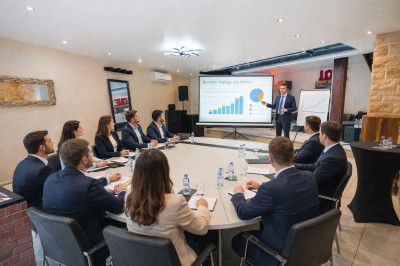 Des professionnels discutent en petits groupes autour de tables hautes dans une cour extérieure ensoleillée.