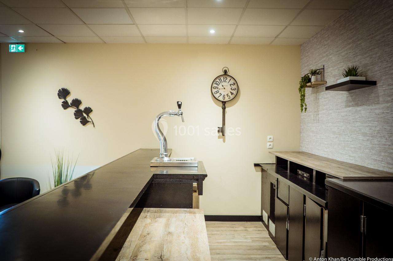 Comptoir de bar en bois avec un robinet de bière, décoré de plantes et d'une horloge murale.