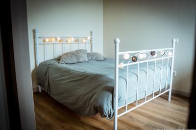 Lit double avec couvre-lit clair dans une chambre lumineuse, équipée d'une lampe sur pied et d'un lit superposé.